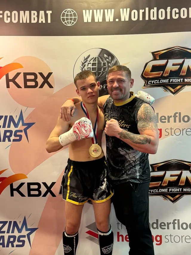 A young fighter with a gold medal beside Darius at a Cyclone Fight Night event
