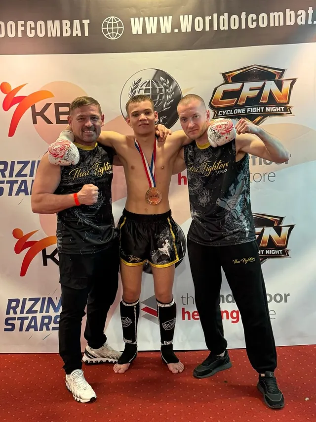 Two fighters and their coach on the podium at a Cyclone Fight Night event