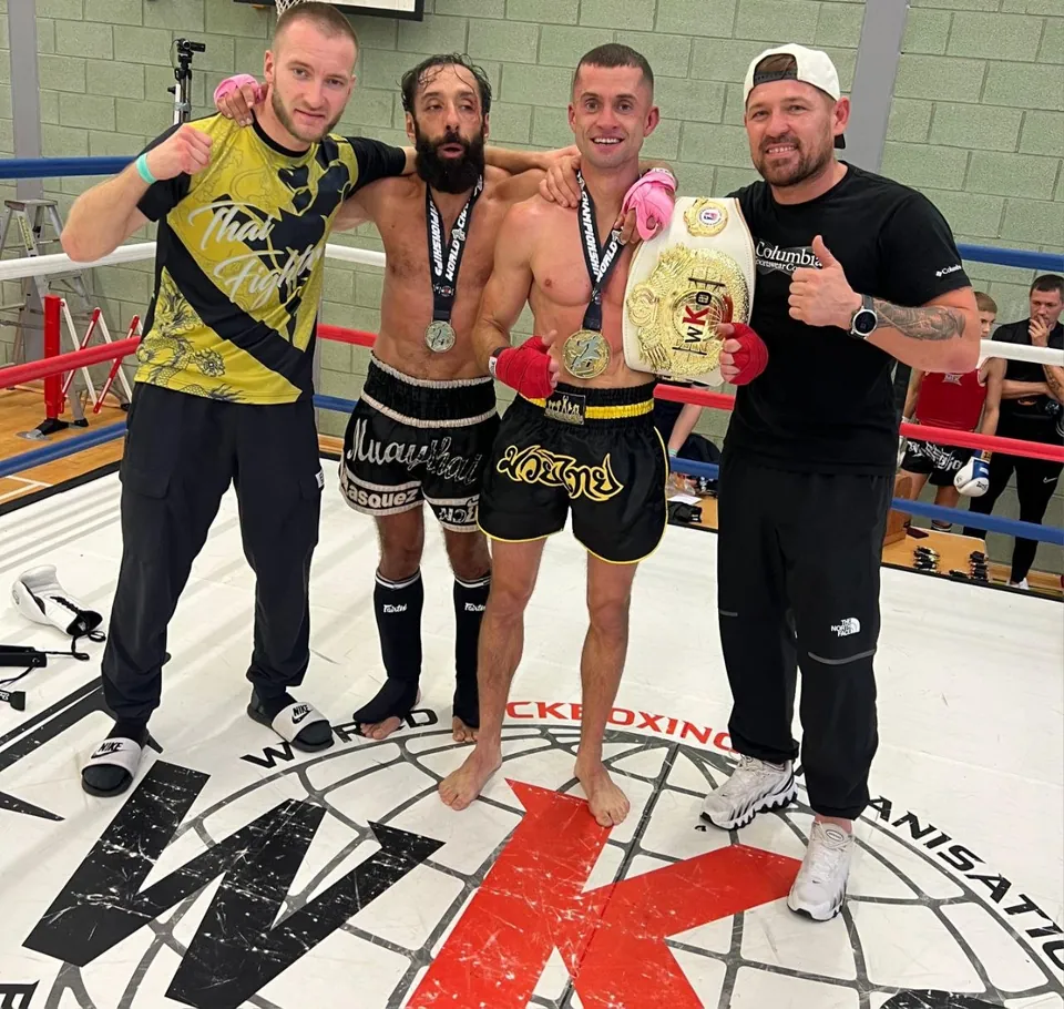 Fighters from the team in the ring at a World Kickboxing Organisation show, one holding a WKO championship belt